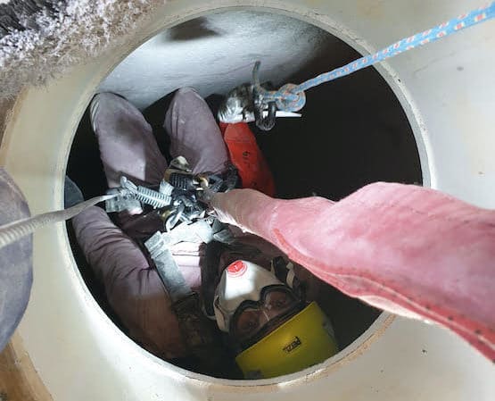 technician entering confined hole